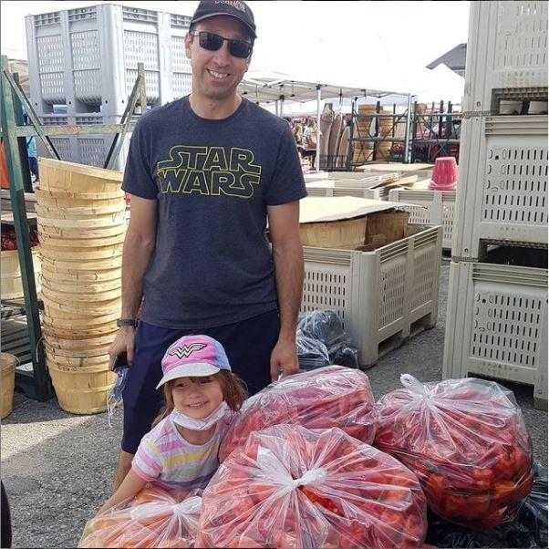 Paul and his daughter at a local farmers market, picking up bags of fresh peppers